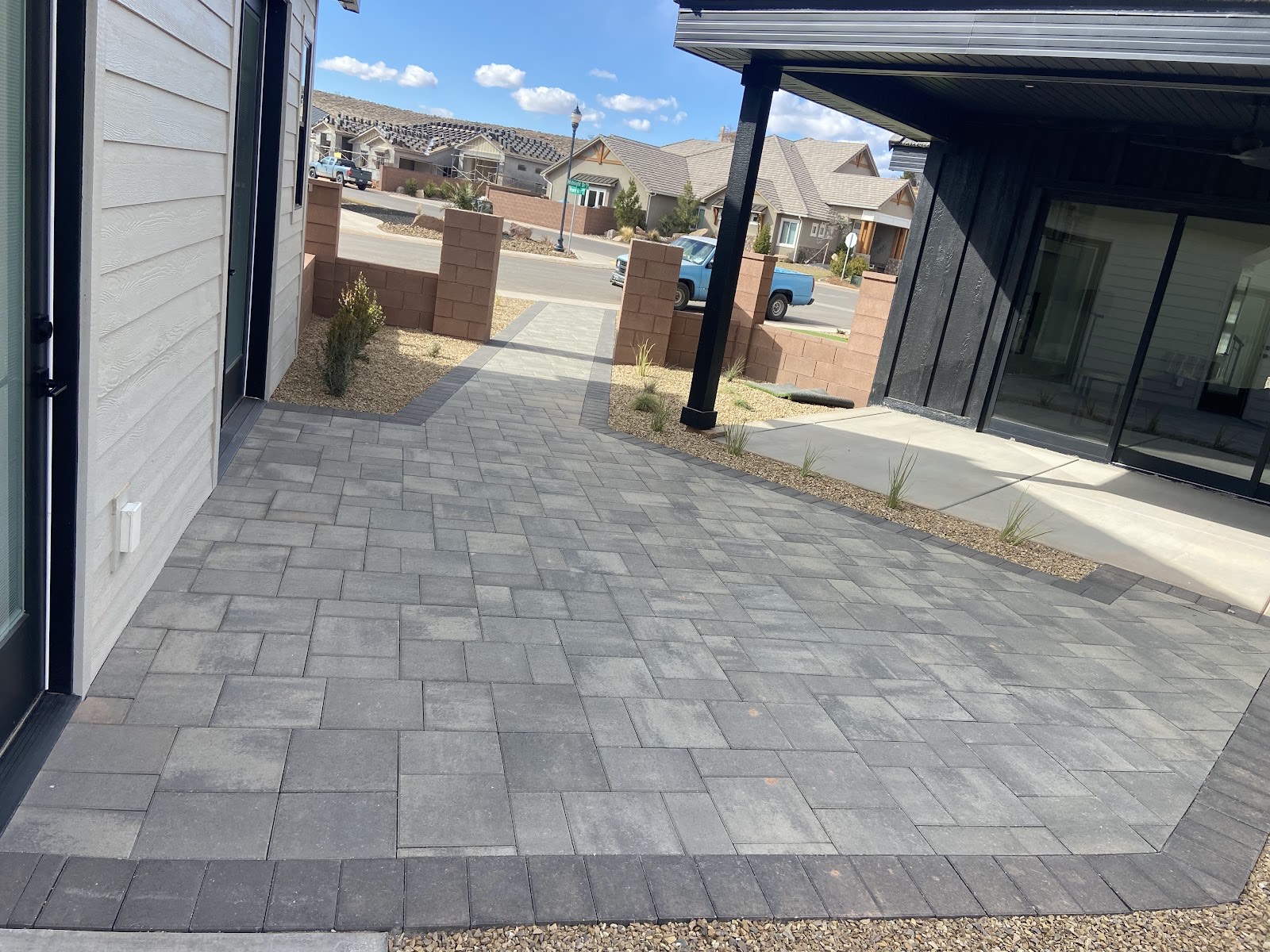 Wide paver walkway and patio beside a modern home
